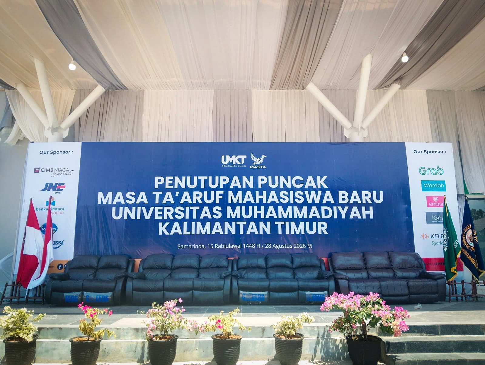 Panggung utama beratap tenda kain putih dengan spanduk besar bertuliskan Penutupan Puncak Masa Ta'aruf Mahasiswa Baru Universitas Muhammadiyah Kalimantan Timur, tanggal 28 Agustus 2026, dikelilingi logo sponsor dan sofa kosong